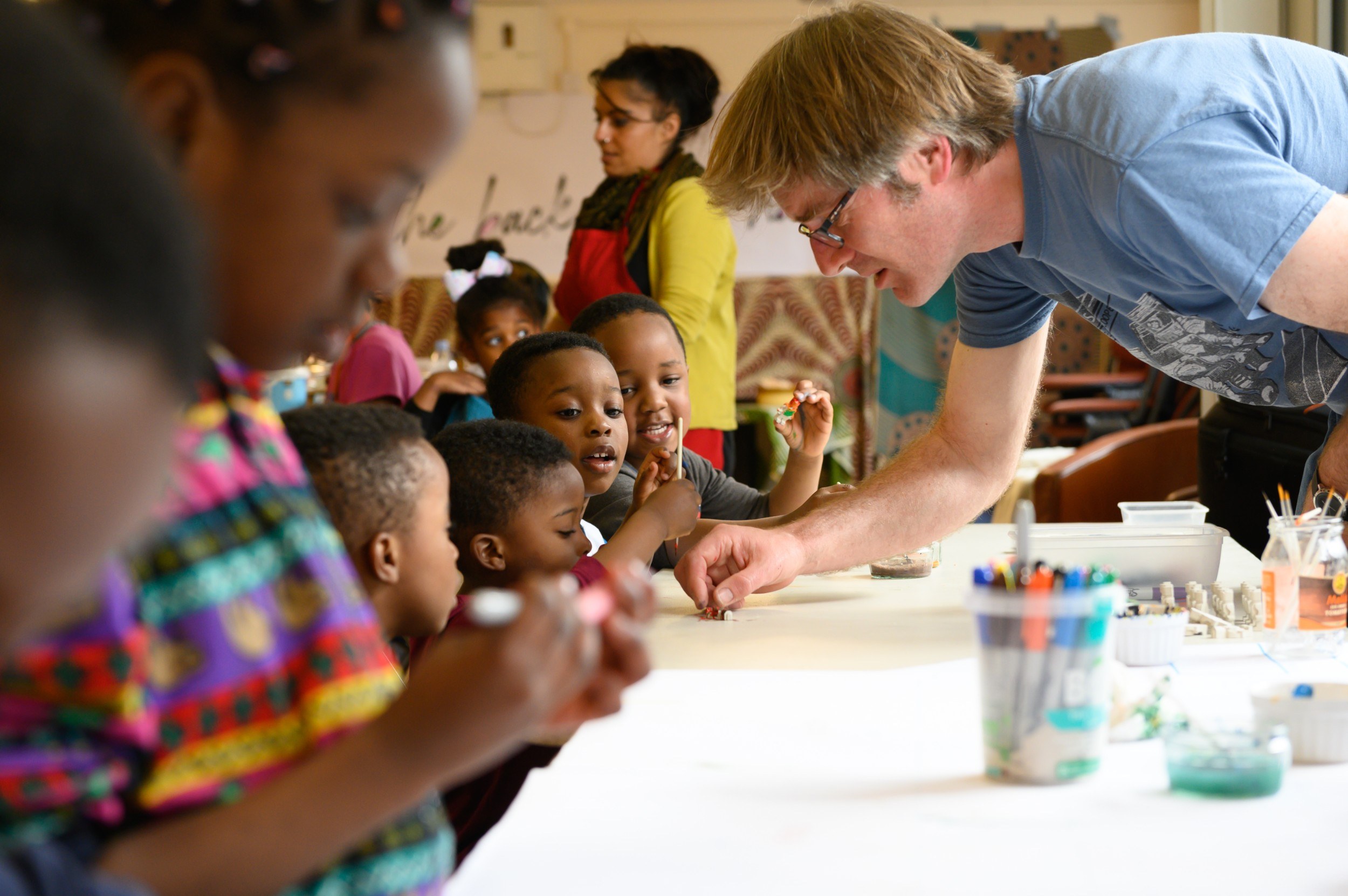 A man leaning over a table and talking with a group of young children
