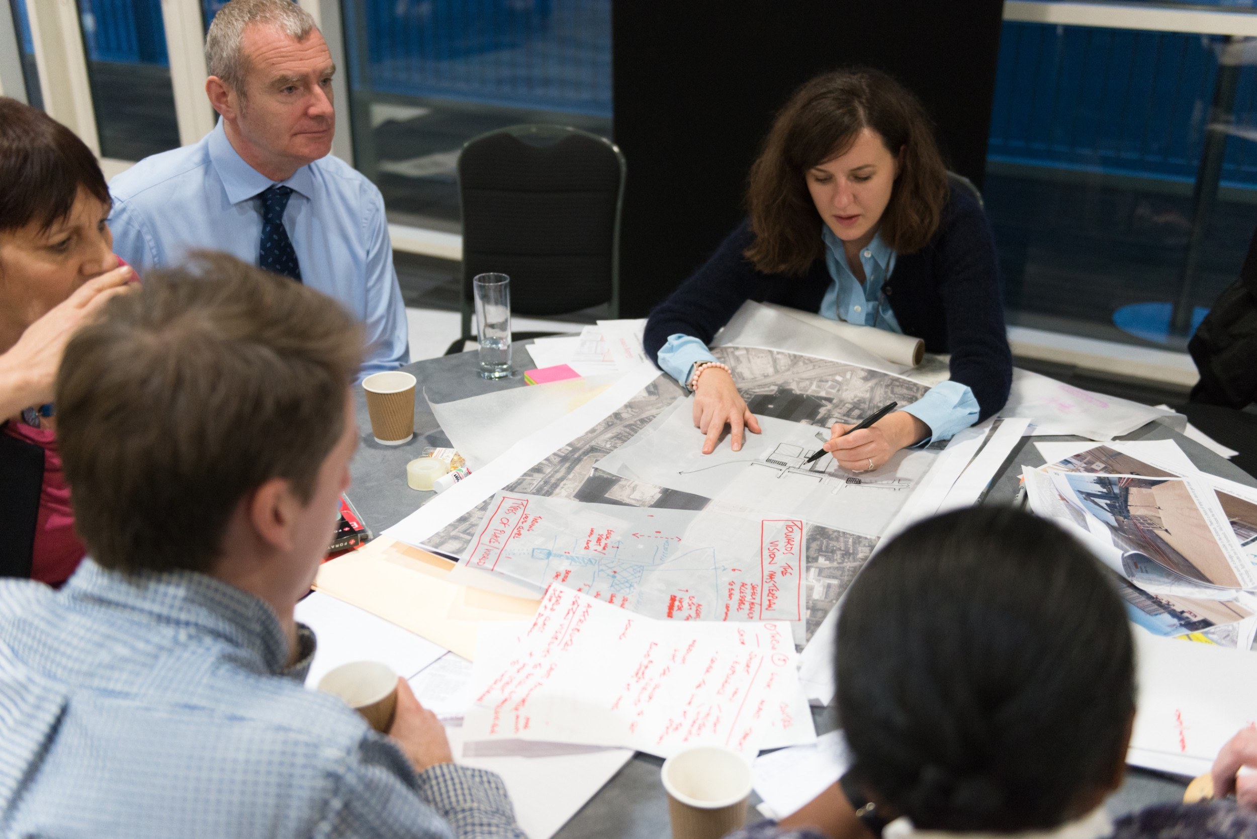 People sitting around a table poring over large diagrams