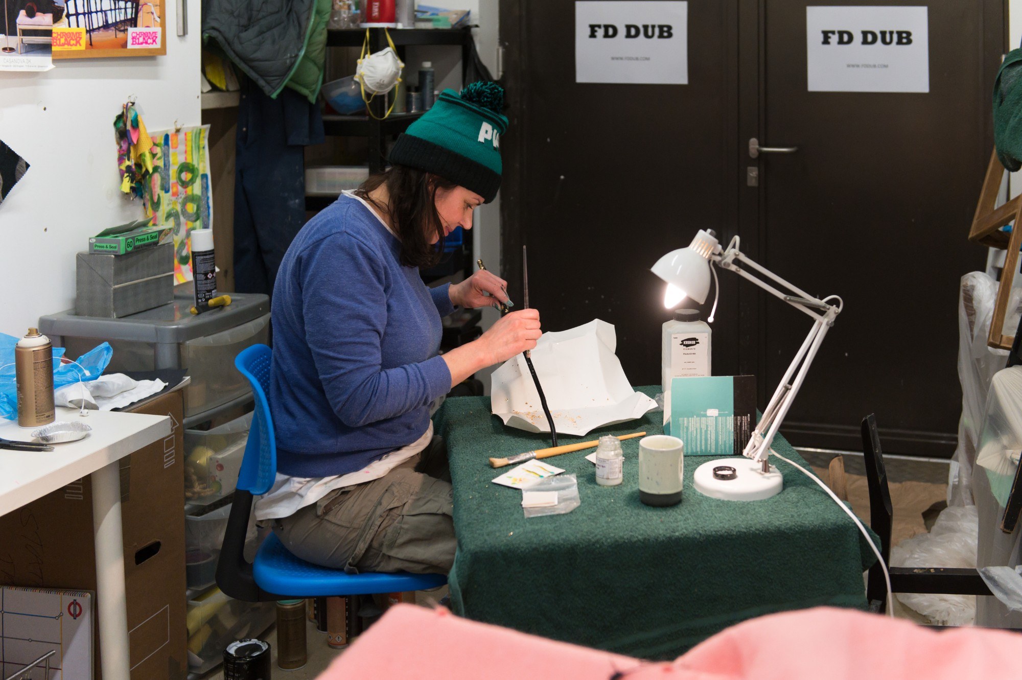 Artist working in studio, adding gilt to a stick