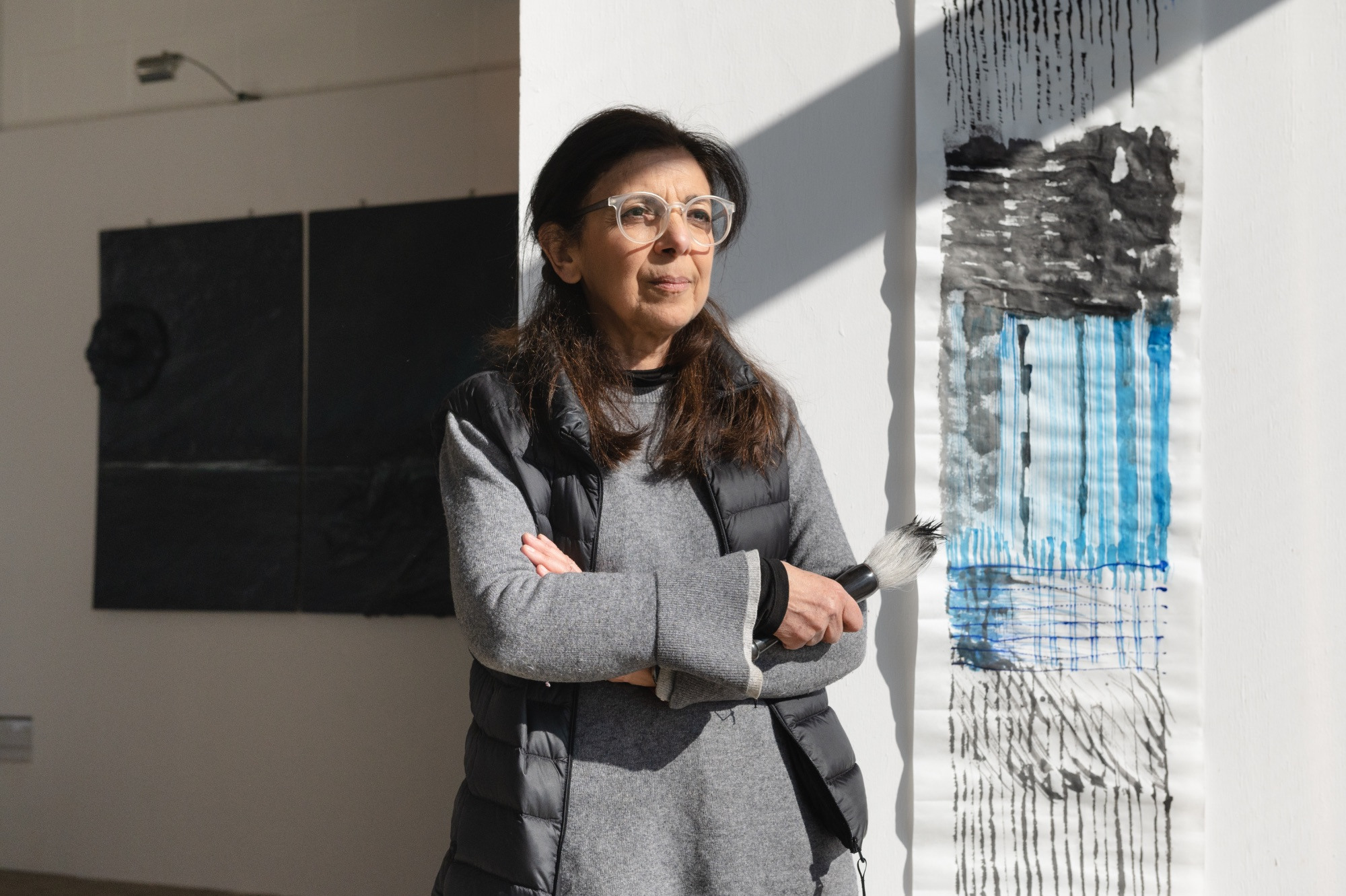 Artist standing by the window next to a painted scroll