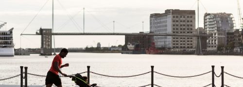 A runner jogging along the docks while pushing a pram