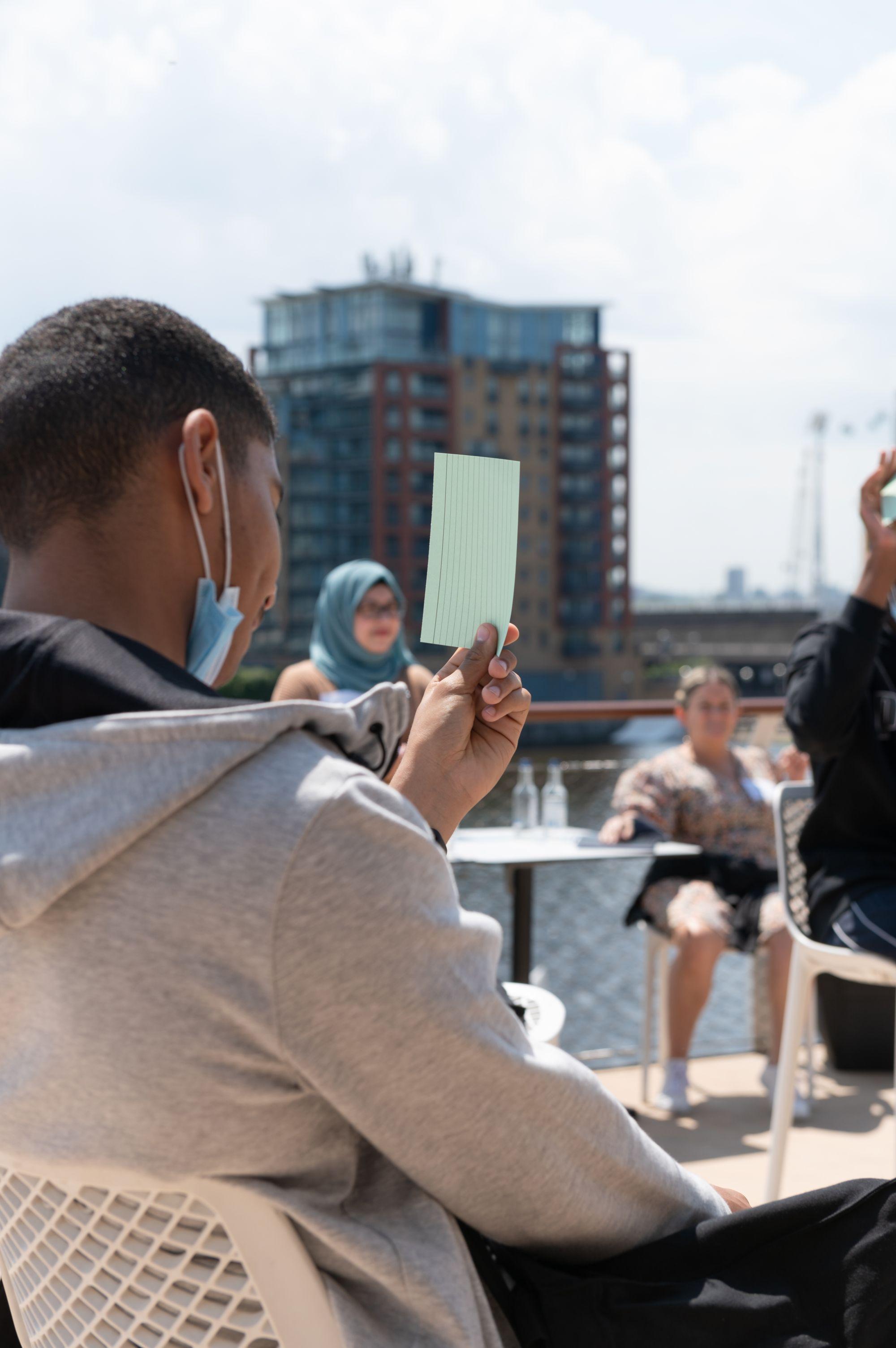 Young man holding up note card during workshop