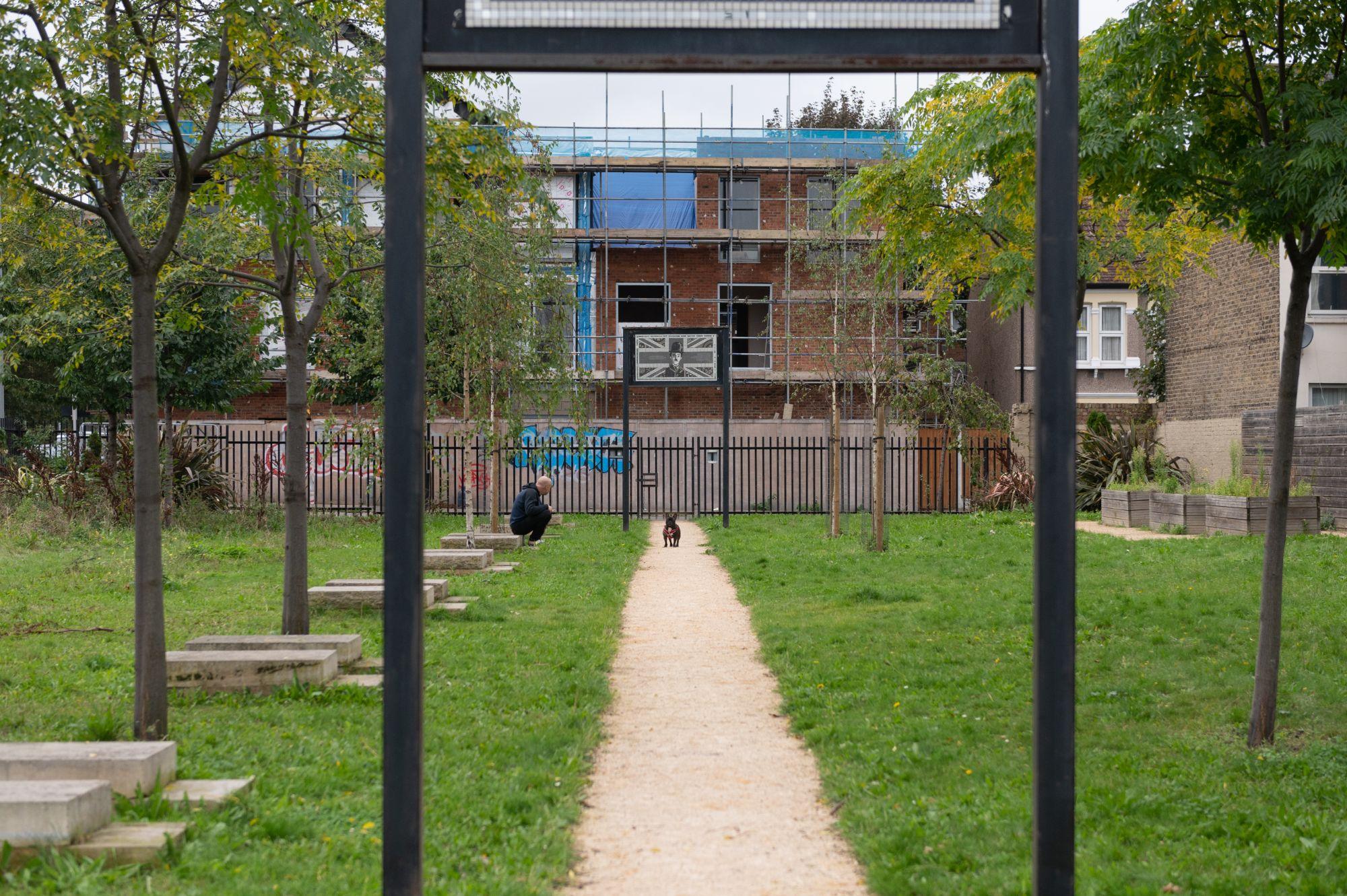 A man with his dog in the memorial garden, on the path under the mosaics