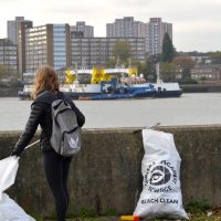 A woman with sacks of rubbish next to the river